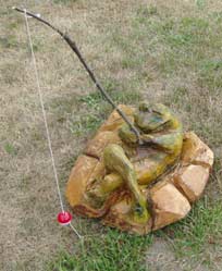 Fishing Frog laying on rocks with fishing pole
